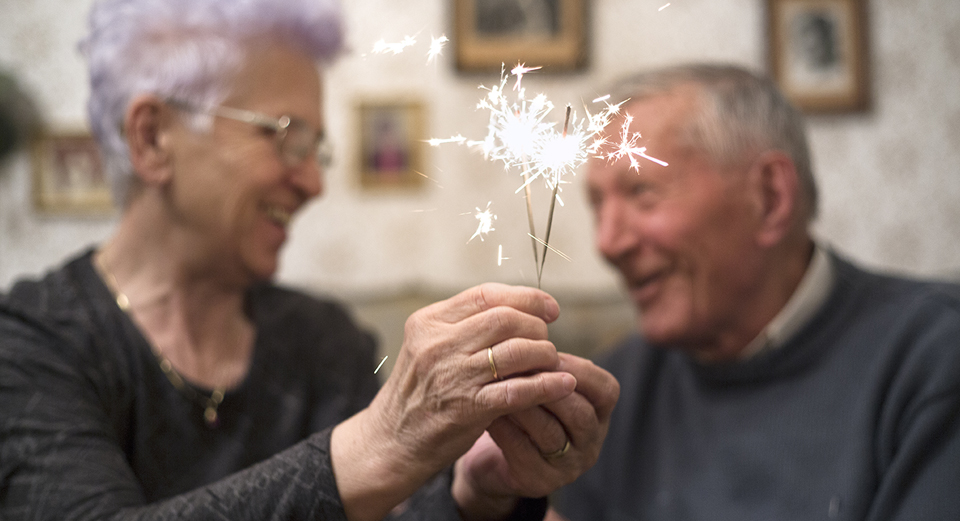 Happy senior couple in their eighties holding sparkler together